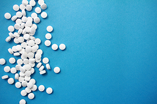White opioid pills are scattered across a blue background.