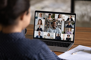 A woman attends a Zoom meeting via laptop.