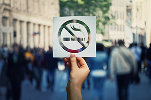 A hand holds a no smoking sign.