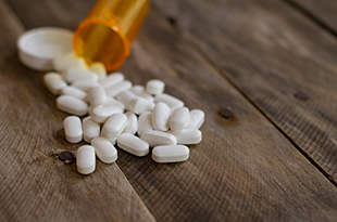 Opioids spilling out from bottle onto table.