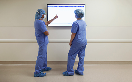 Health care providers view patient data on a monitor.