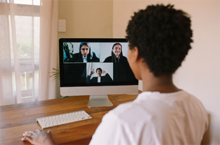 A woman attends a Zoom meeting at her laptop.