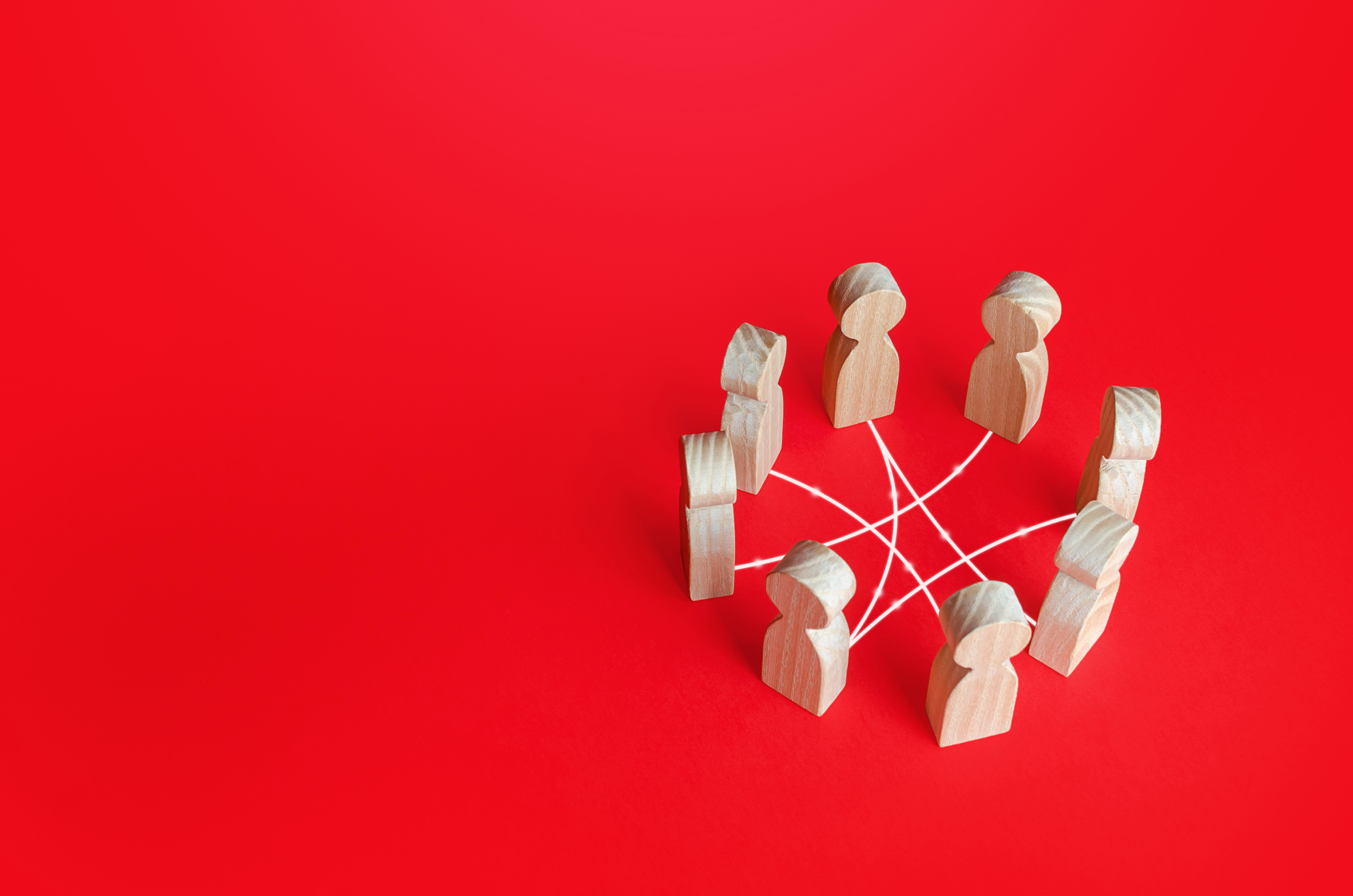 A group of wooden figures forms a network on a red background.