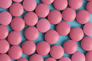 Medium-pink round pills are scattered across a light blue background.
