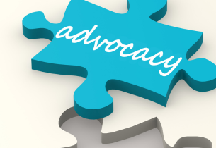 An aqua puzzle piece with the word "advocacy" in white script sits near an open spot in a white puzzle.