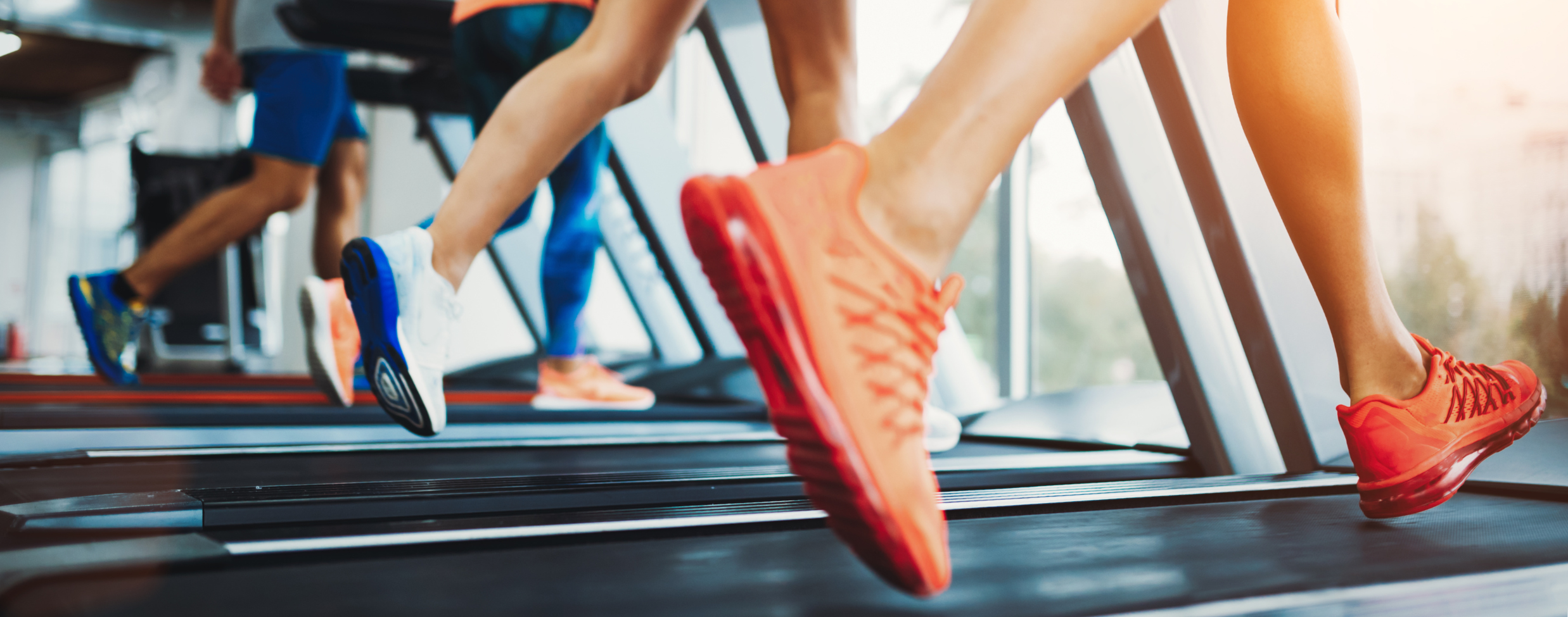 A few of feet running on a row of treadmills.