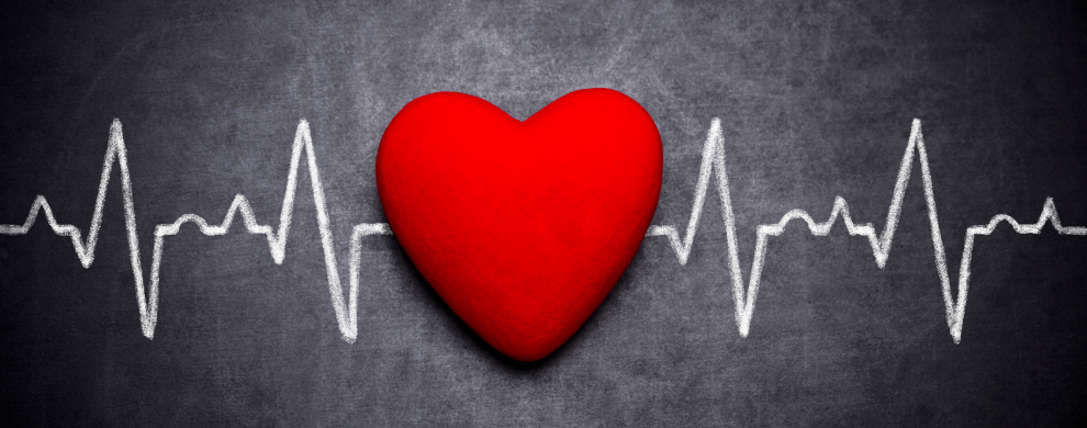 A red heart is in the middle of a heart rate monitor line written in white chalk on a chalk board.